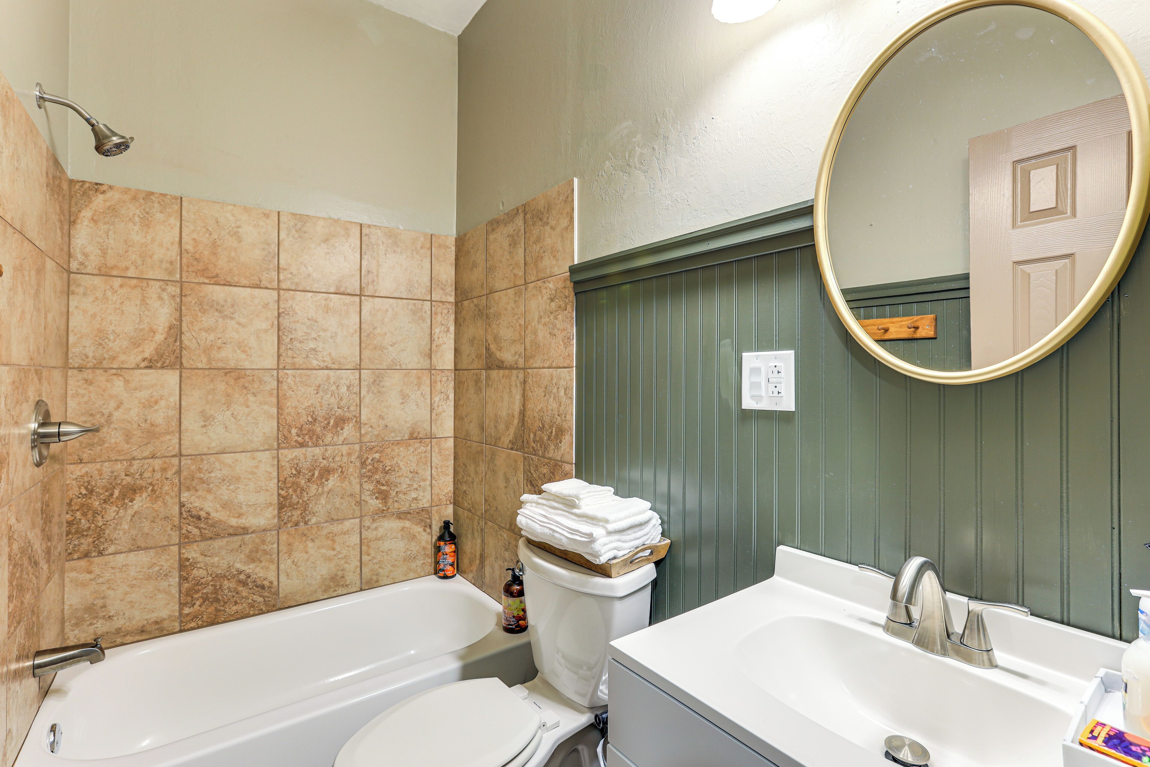 A bathroom with a bathtub, toilet, and sink, with a mirror above the sink.