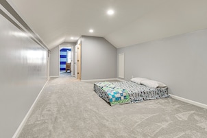 Quarto com uma cama de solteiro, uma porta que dá para outro cômodo e piso coberto por carpete.