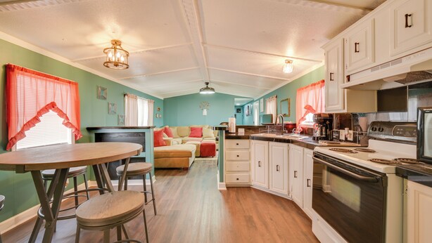 A kitchen with a dining area, a stove, and a sofa.