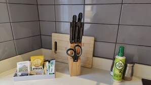 A kitchen counter with a cutting board, a knife block, a bottle of cooking oil, and a box of baking supplies. - Leicester Square 2nd Floor Studio (London)