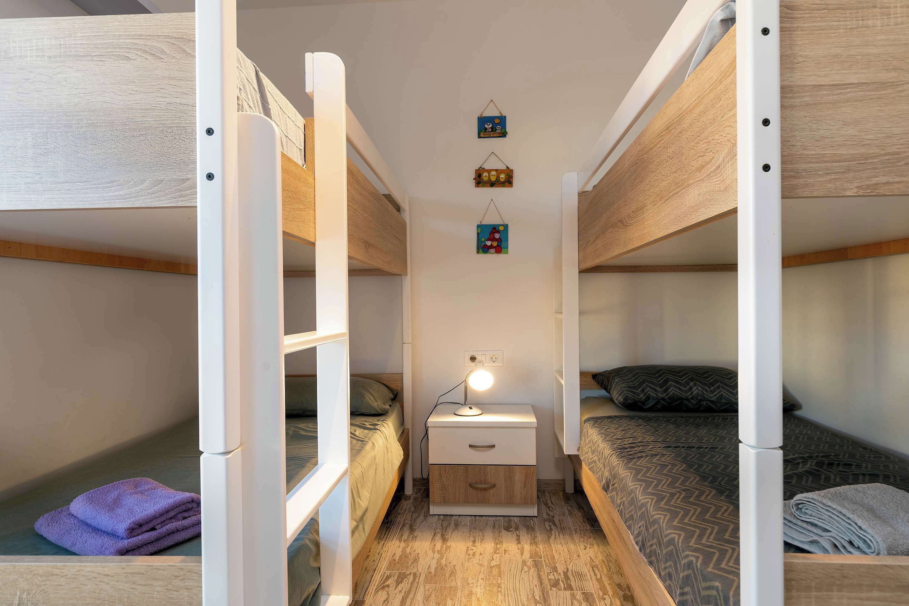 A bunk bed room with a nightstand and a lamp.