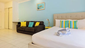 A hotel room with a bed, a sofa, a small table, and a picture on the wall. - Cozy studio in gorgeous Port Douglas with WiFi, fitness room, AC (Port Douglas)
