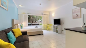 A modern living room with a sofa, a bed, a TV, and a dining area. - Cozy studio in gorgeous Port Douglas with WiFi, fitness room, AC (Port Douglas)
