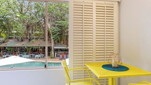 A yellow table and chair set with a view of an outdoor pool and dining area. - Cozy studio in gorgeous Port Douglas with WiFi, fitness room, AC (Port Douglas)