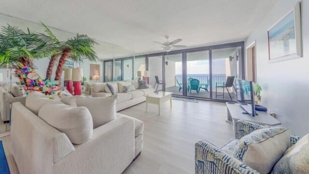 Ein geräumiges Wohnzimmer mit einer großen Couch, einem Couchtisch und einem Balkon mit Sitzgelegenheiten.