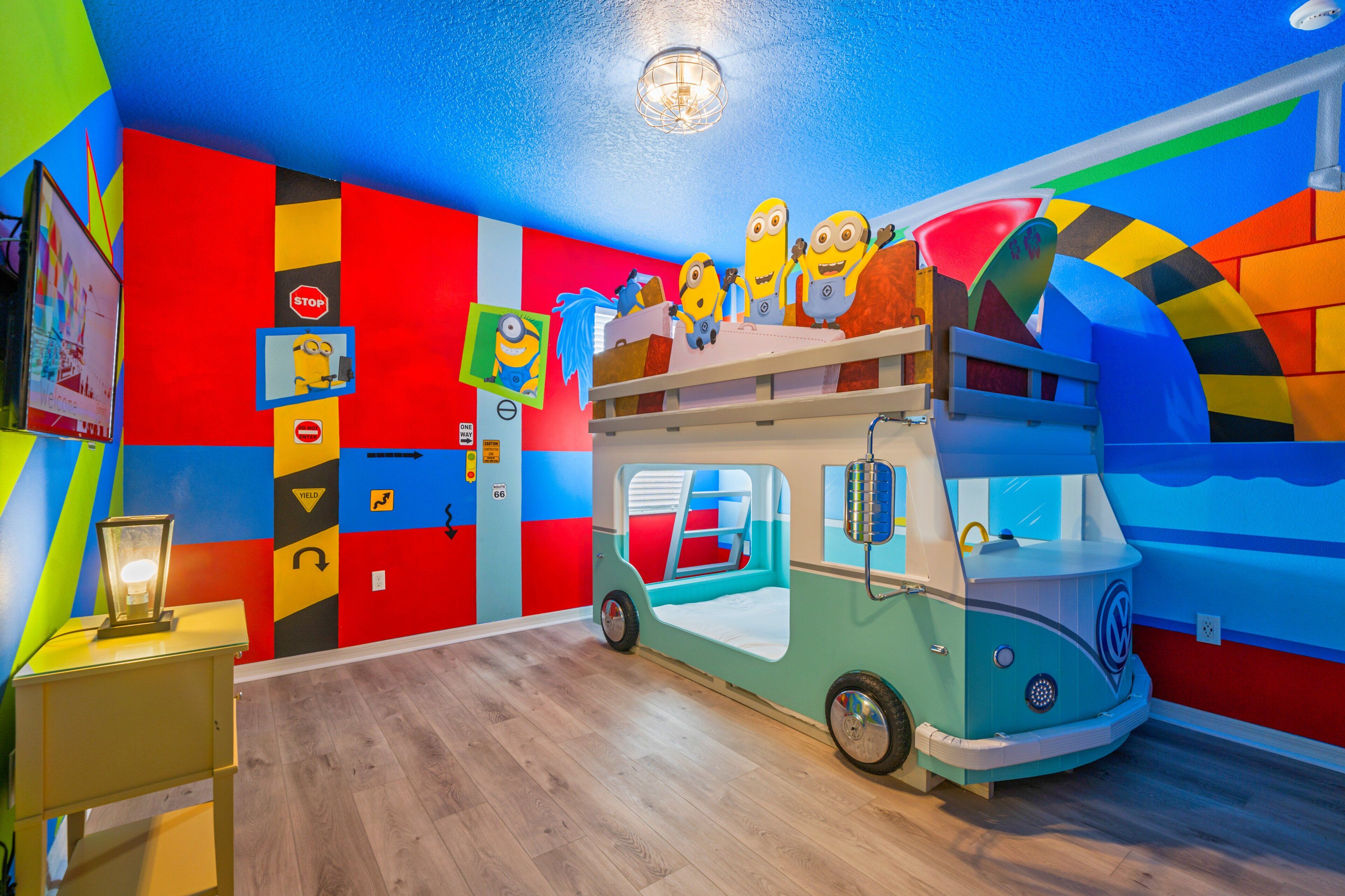 A children's playroom with colorful walls, a toy bus, and minion decorations.