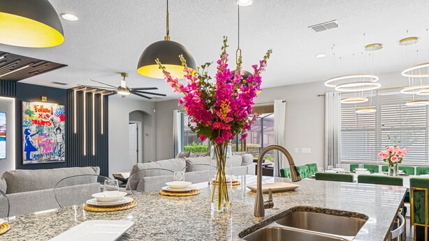 Eine moderne Küche mit Granit-Arbeitsplatten, einer Edelstahl-Spüle und einer Vase mit rosa Blumen.