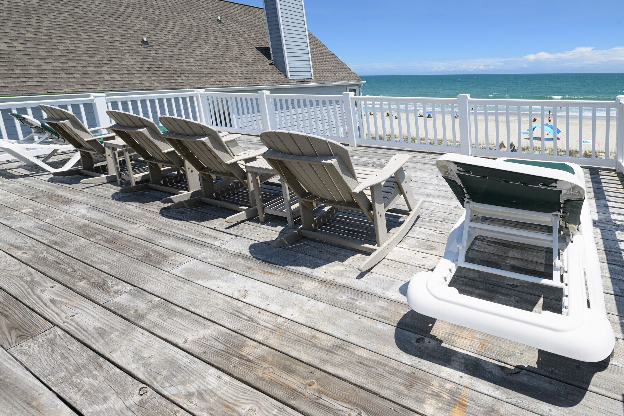 A wooden deck with Adirondack chairs and a small boat.