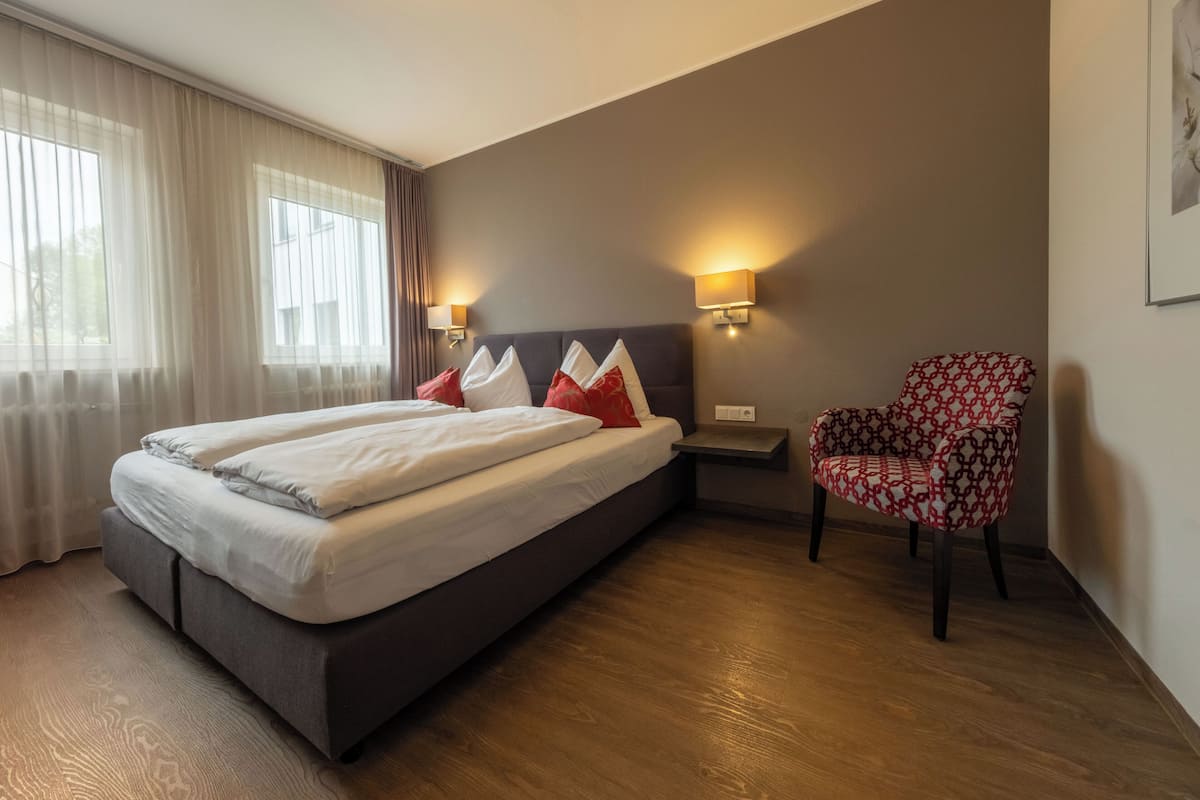 Habitació d'hotel amb un llit, una cadira i una taula de nit.