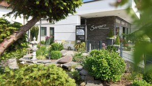 A modern hotel with a stone facade, a garden with a pond, and a sign indicating check-in and check-out times. - Hotel Staffler & Schreiners Restaurant (Odelzhausen)