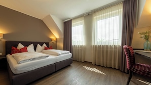 A hotel room with a bed, a chair, a nightstand, and a window with curtains. - Hotel Staffler & Schreiners Restaurant (Odelzhausen)