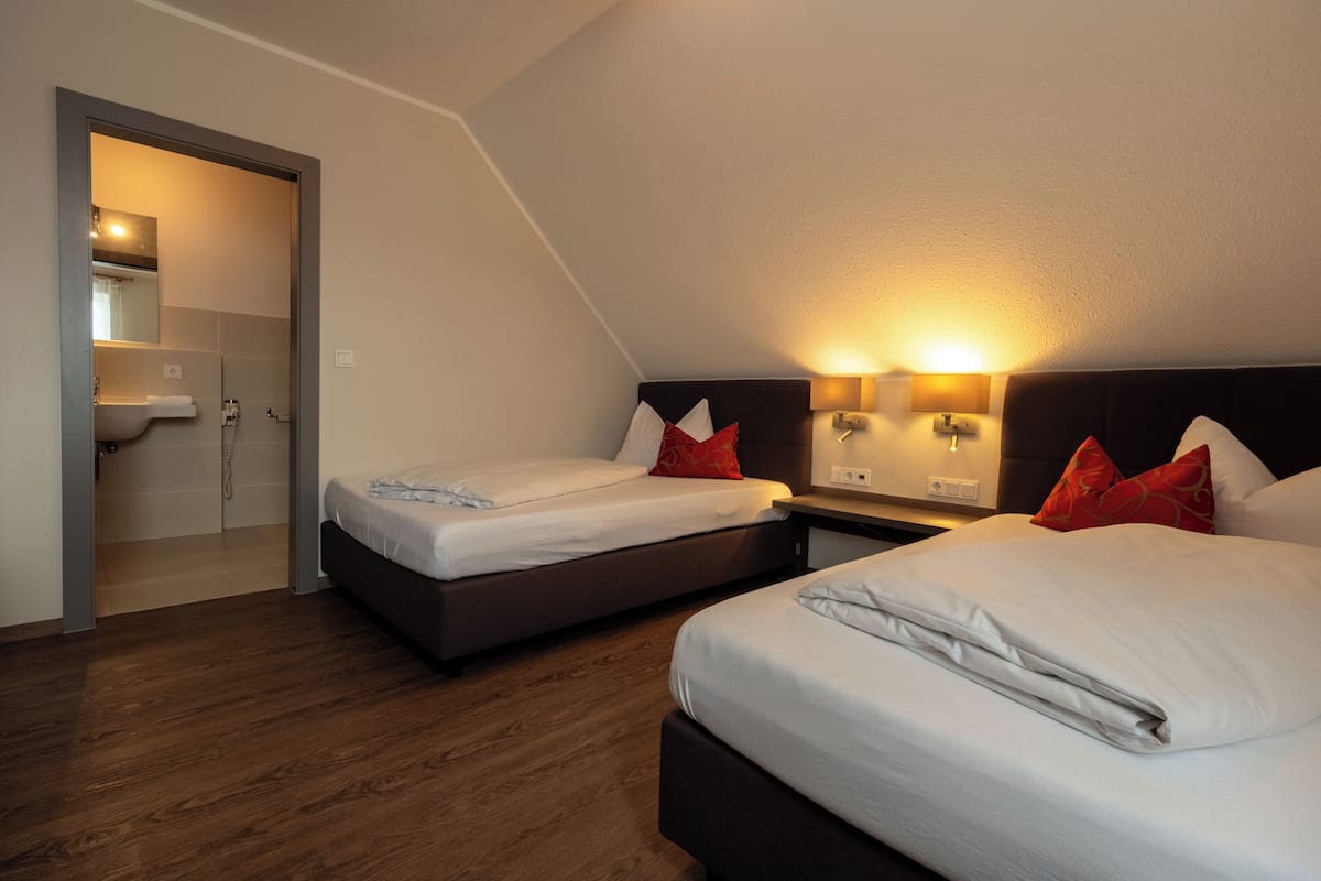 Habitació d'hotel amb dos llits, un bany i un terra de fusta.