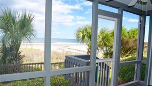 Un espace extérieur abrité, avec vue sur la plage, une clôture en bois et quelques plantes.