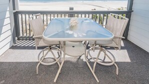 Un balcón con mesa y sillas que da a una playa.