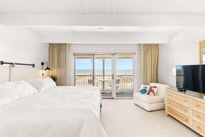 A hotel room with a large bed, a TV, a small sofa, and a balcony with a view of the beach. - Beach Place 14 2 Bedroom Townhouse (Ocean City)