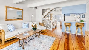 A spacious living area with a sofa, coffee table, and a kitchen area with bar stools. - Beach Place 14 2 Bedroom Townhouse (Ocean City)