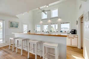 Une cuisine moderne dotée d’un îlot central, de tabourets de bar et d’un ventilateur de plafond.