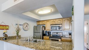 Eine moderne Küche mit Granit-Arbeitsplatten, Edelstahlgeräten und Holzschränken.