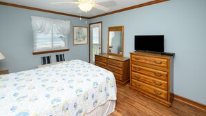Ein Schlafzimmer mit Bett, Schminktisch, Fernseher und Deckenventilator.