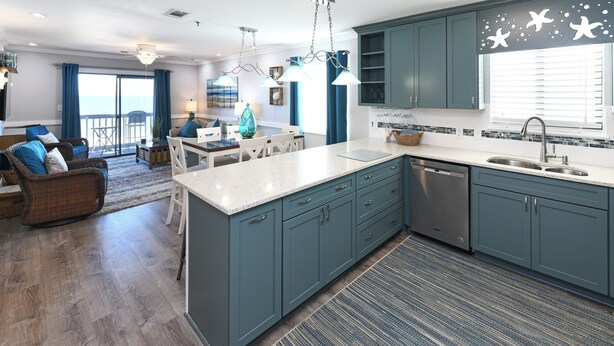 Une cuisine moderne avec des meubles de couleur turquoise, un grand îlot central et une vue sur l’extérieur.