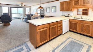 A spacious kitchen with wooden cabinets, a large island, and a view to the outside.