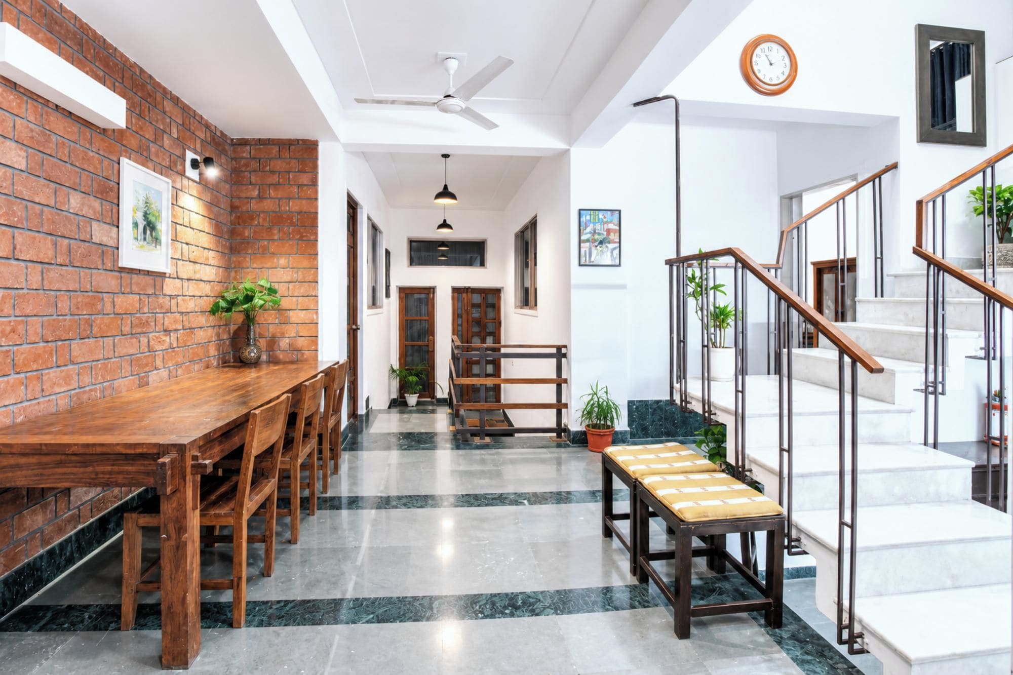 A modern interior with a brick wall, wooden dining table, and a staircase with metal railings.