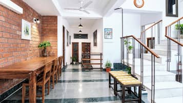 A modern interior with a brick wall, wooden dining table, and a staircase with metal railings.