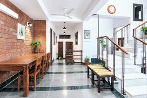 Un interior moderno con pared de ladrillo, mesa de comedor de madera y escalera con barandilla de metal.