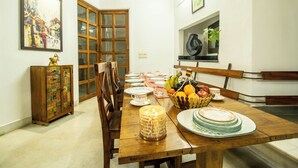 Un comedor con una mesa de madera preparada para una comida, una cesta de frutas y un mueble con azulejos decorativos.