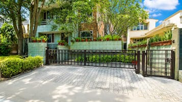 Una zona residencial privada con un camino pavimentado, plantas en macetas y un cielo despejado.