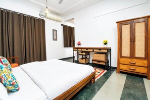 Habitación de hotel con cama, escritorio, armario y aire acondicionado de pared.