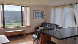 A modern kitchen with a dining area, a bench, and a view of the countryside. - 2 Bed Cottage - Sleeps 4 - Garden, Parking Wifi (Swansea)