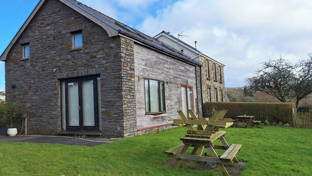 A stone house with a large front door, a small porch, and a picnic table in the yard. - 2 Bed Cottage - Sleeps 4 - Garden, Parking Wifi (Swansea)