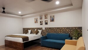 A modern hotel room with a wooden floor, a bed, a blue sofa, and a yellow armchair.