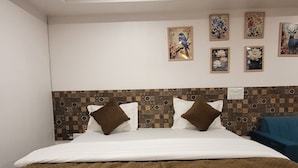 A hotel room with a large bed, a patterned headboard, and several wall-mounted artworks.