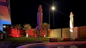 A nighttime outdoor area with two umbrellas, a pool, and decorative lighting. - Wellness in the Eifel for Ages 16 and Up (Mechernich)