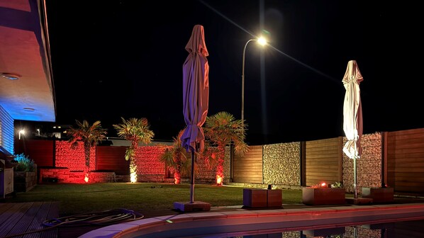 A nighttime outdoor area with two umbrellas, a pool, and decorative lighting. - Wellness in the Eifel for Ages 16 and Up (Mechernich)