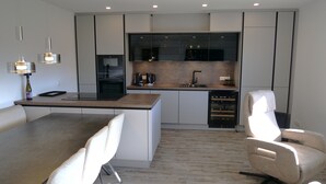 A modern kitchen with a central island, built-in appliances, and a dining area with a table and chairs. - Wellness in the Eifel for Ages 16 and Up (Mechernich)