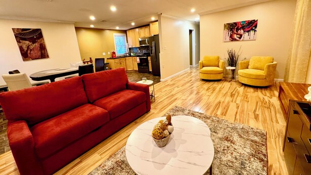 A modern living room with a red sofa, a round coffee table, and yellow armchairs. - Charming Urban3-bedroom  apartment in Hempstead with WiFi and AC (Hempstead)