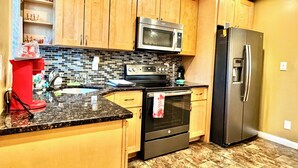 A kitchen with wooden cabinets, a stainless steel refrigerator, a microwave, and a stove. - Charming Urban3-bedroom  apartment in Hempstead with WiFi and AC (Hempstead)