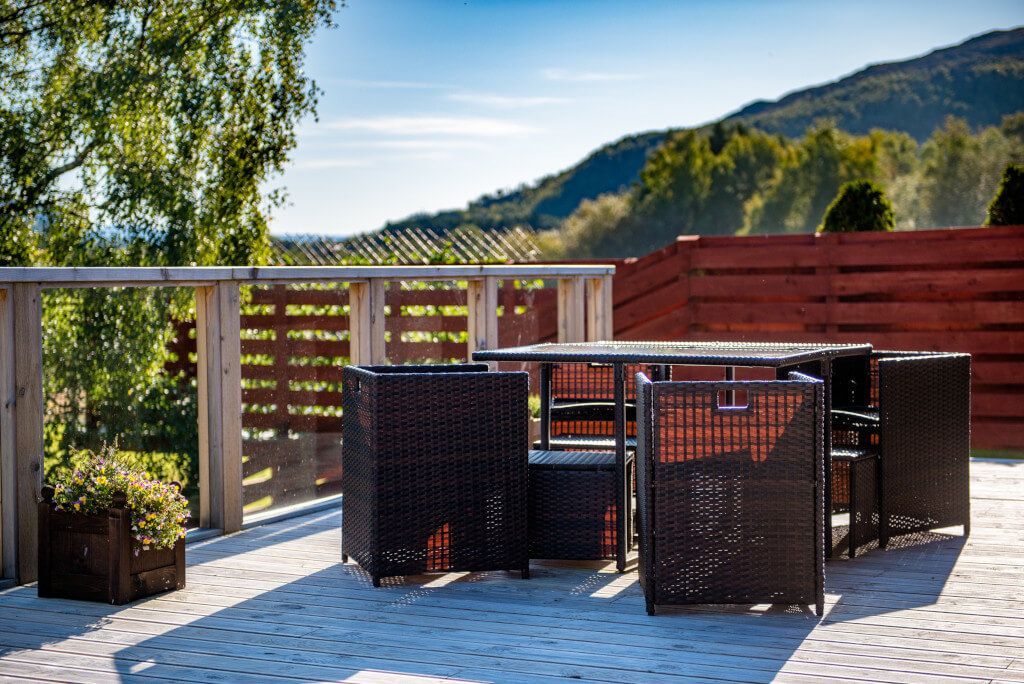 An outdoor patio with wicker furniture and a wooden deck.