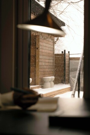 A bathroom with a wooden exterior wall, a white toilet, and a hanging light fixture.