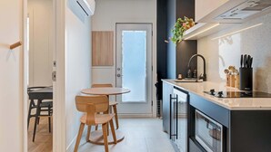 A modern kitchen with a built-in oven, a sink, and a countertop. There is a dining area with a table and chairs.