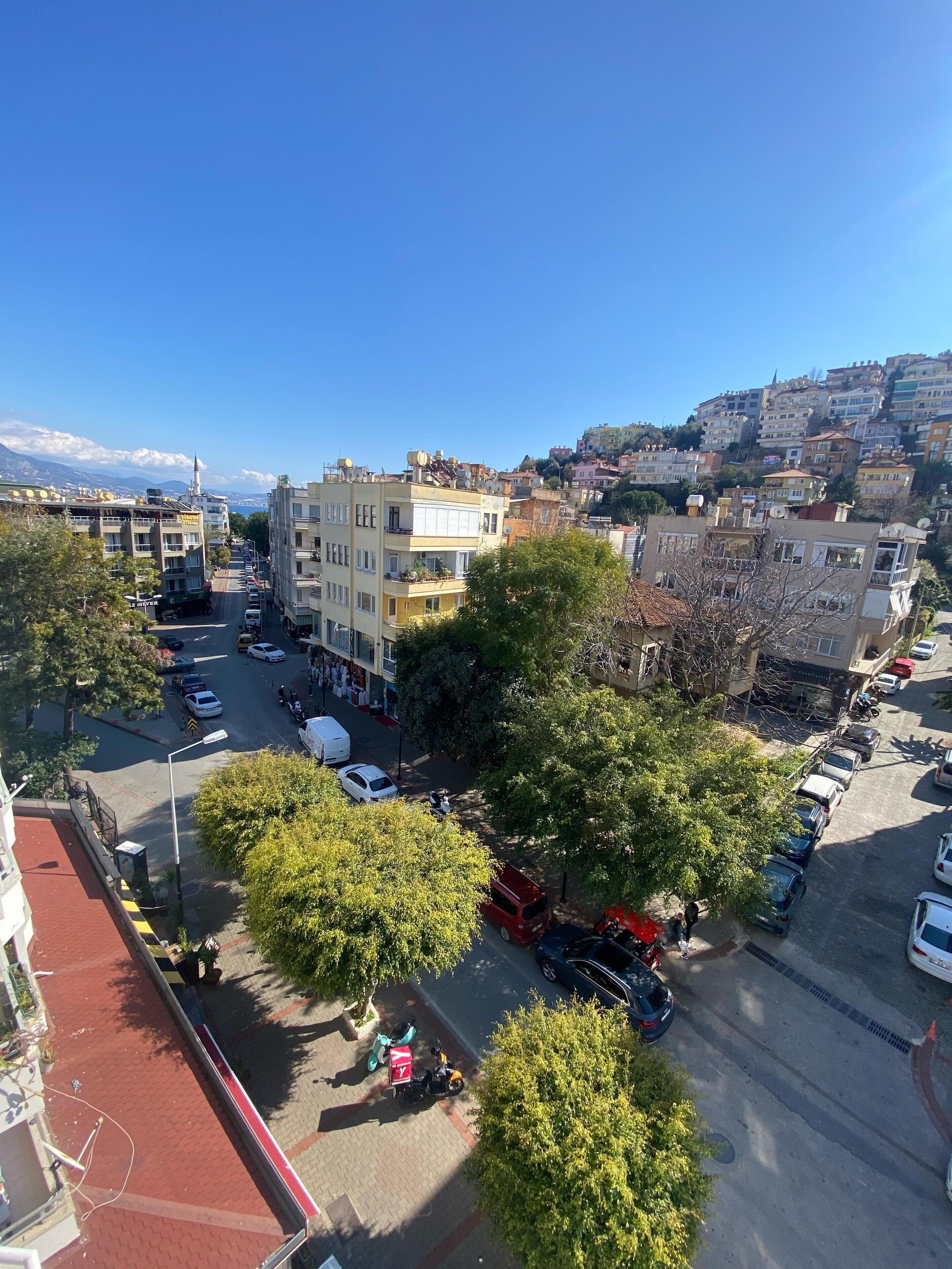 A cityscape with multi-story buildings, a clear sky, and a hilly backdrop.