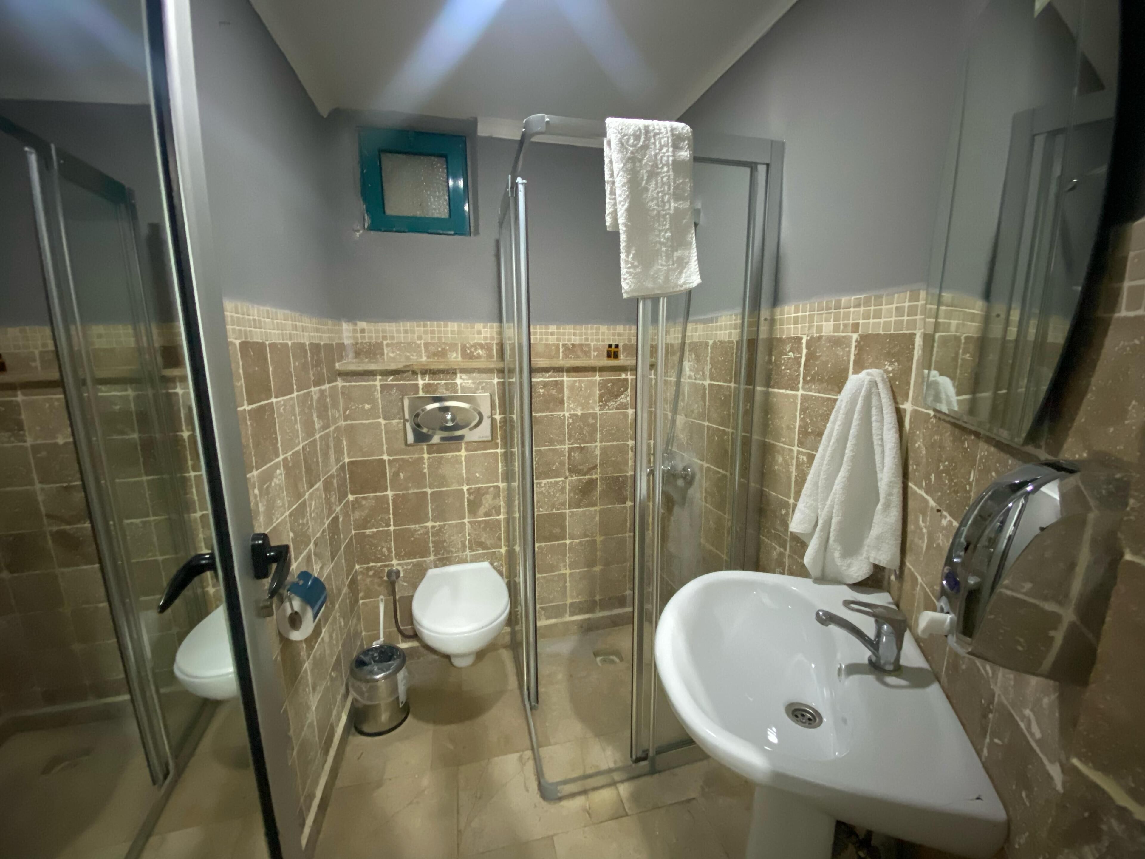Ein Badezimmer mit einer gläsernen Dusche, einem weißen Waschbecken und einer Toilette.