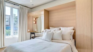 Un dormitorio moderno con una cama grande, un escritorio y una ventana con cortinas.