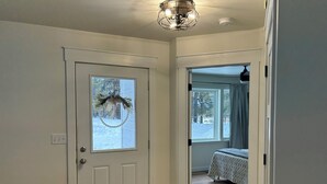 A hallway leading to a bedroom with a bed, a door with a decorative wreath, and a window with curtains. - Private, luxury, 4-bedroom home minutes from downtown Bigfork (Bigfork)
