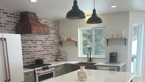 A kitchen with a large island, a brick wall, and a window. - Private, luxury, 4-bedroom home minutes from downtown Bigfork (Bigfork)