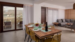 A modern dining area with a wooden table, yellow chairs, and a view of the outdoors through large sliding glass doors.