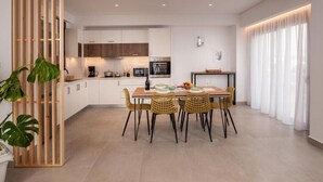 A modern kitchen with white cabinets, a wooden dining table, and yellow chairs.
